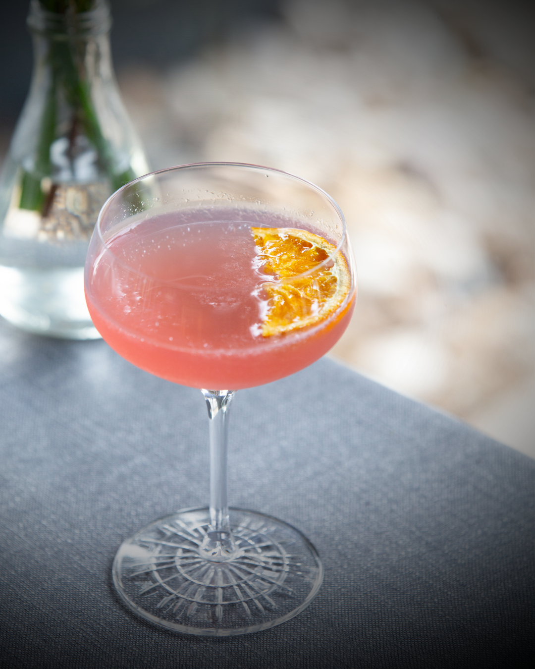 Dried fruit slice in a pink cocktail, a half dried orange slice, premium cocktail garnish, dehydrated fruits