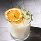 Cocktail with an orange slice and thyme garnish on a marble surface