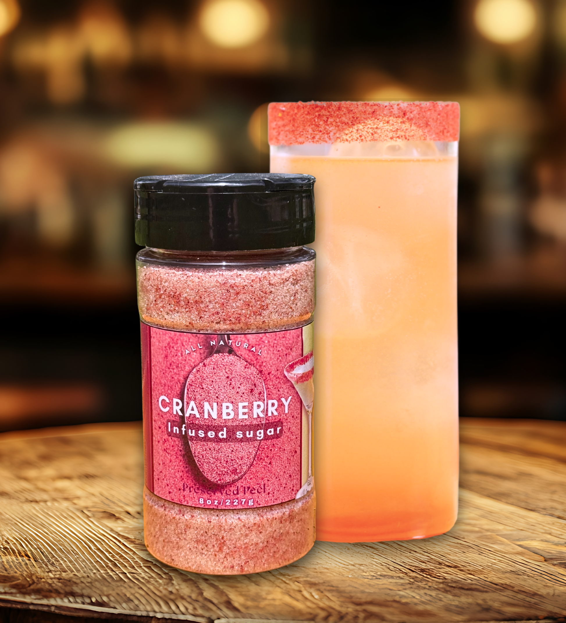 Jar of cranberry infused sugar next to a cocktail on a wooden surface with a blurred background