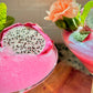 Two pink cocktails with dragon fruit and flowers on a wooden table.